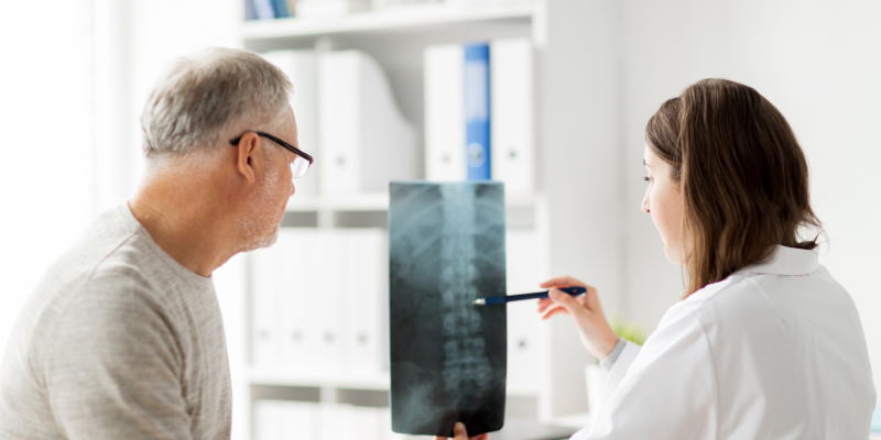 Image of a doctor showing x-ray of spine to senior man at hospital illustrates the Minimally Invasive Spine Surgery types for spine surgery.